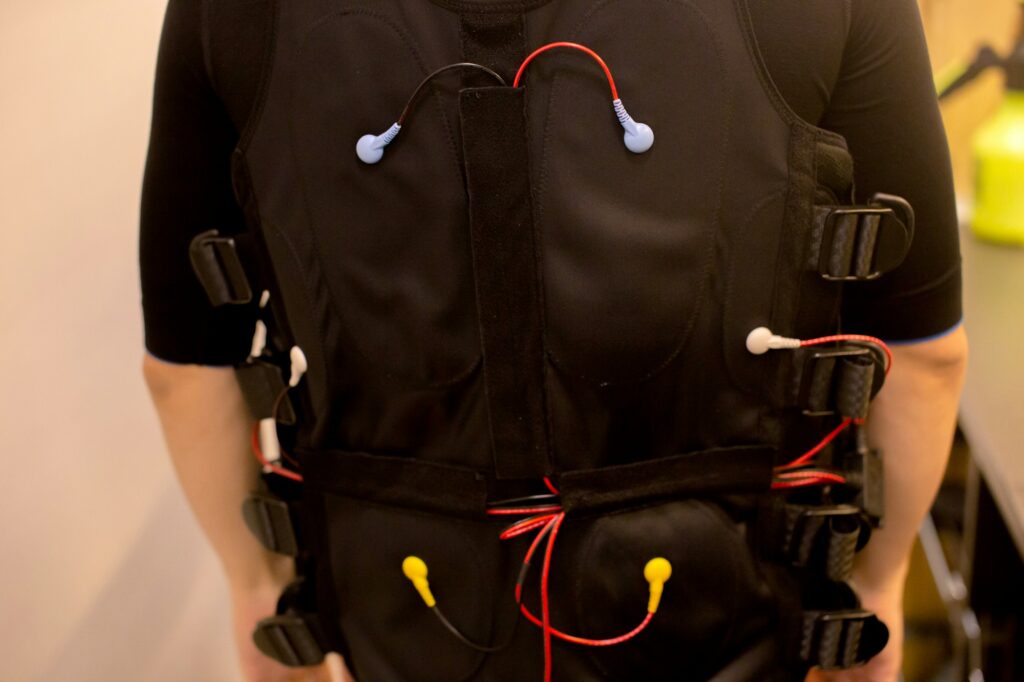 Close-up of fit man in black full body suit for ems training and muscular electrode technology.