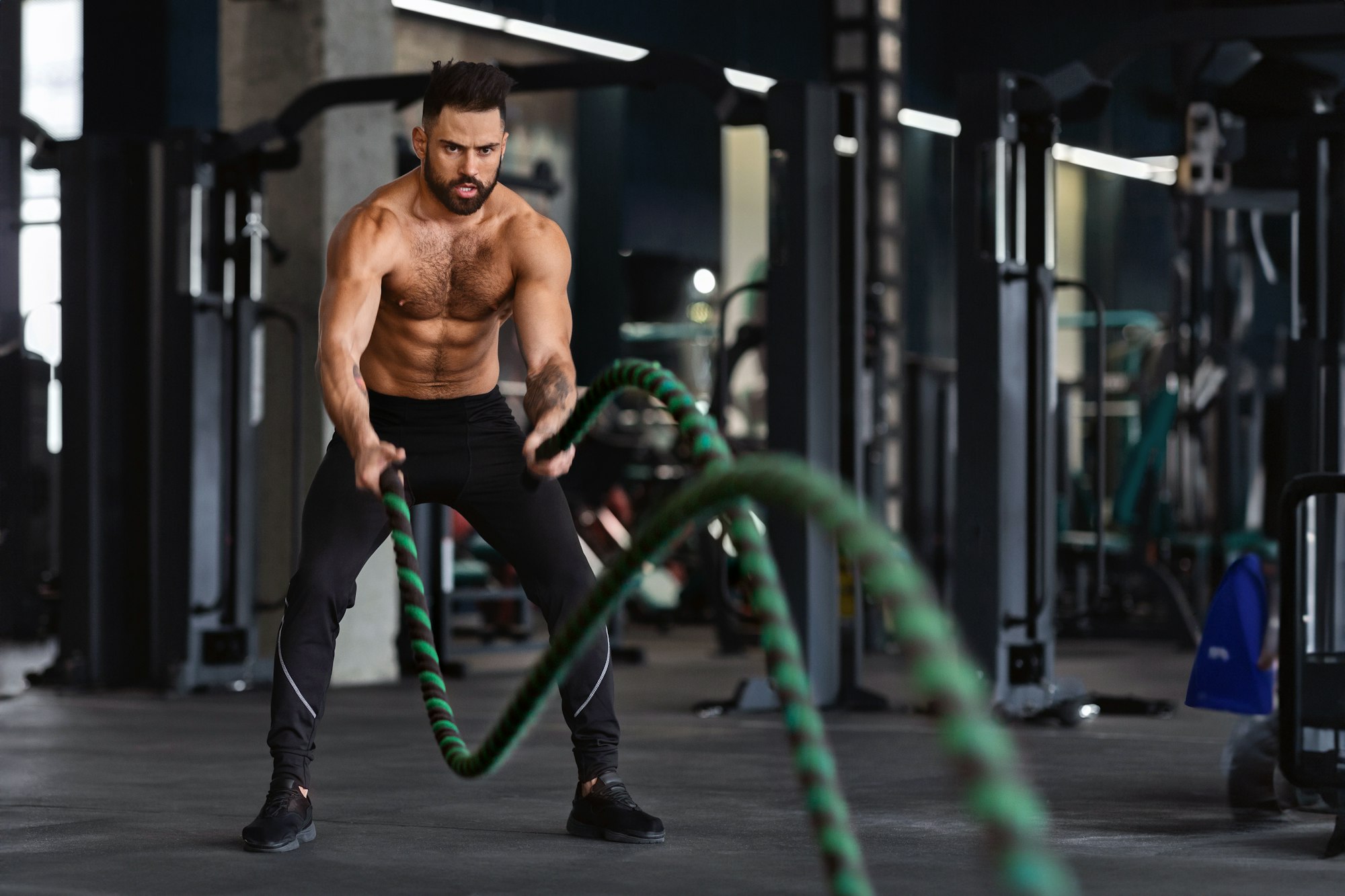 Fitness man working out with battle ropes at gym