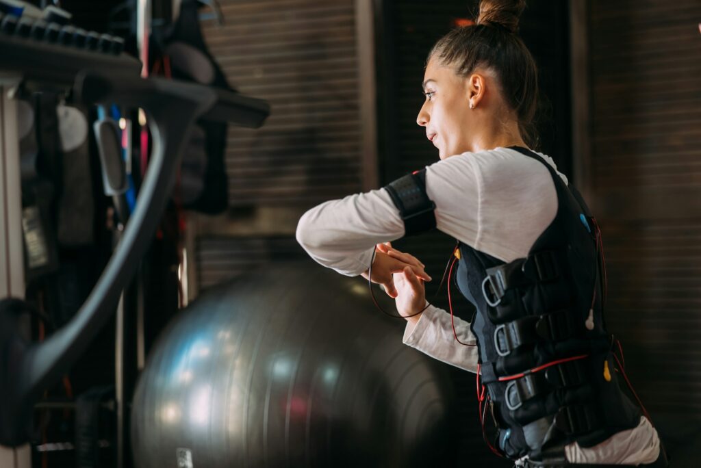 EMS training. Girl doing exercises in a suit with cables