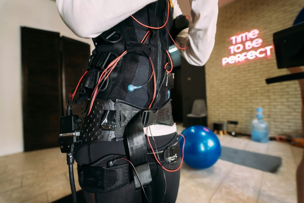 EMS training. Girl doing exercises in a suit with cables