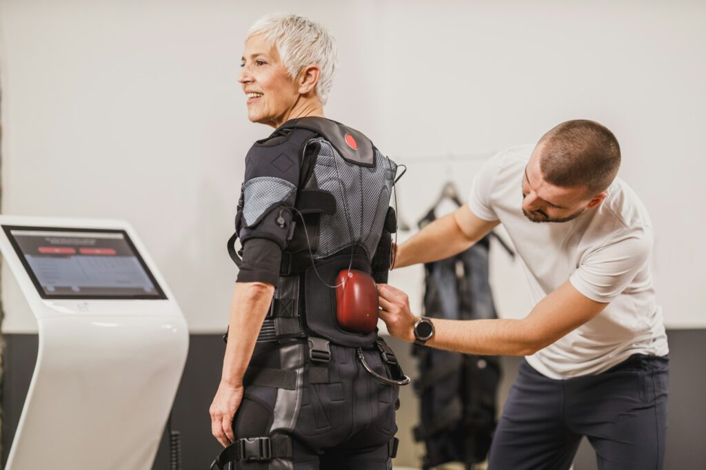 Fitness Instructor Putting An Ems Suit To A Woman