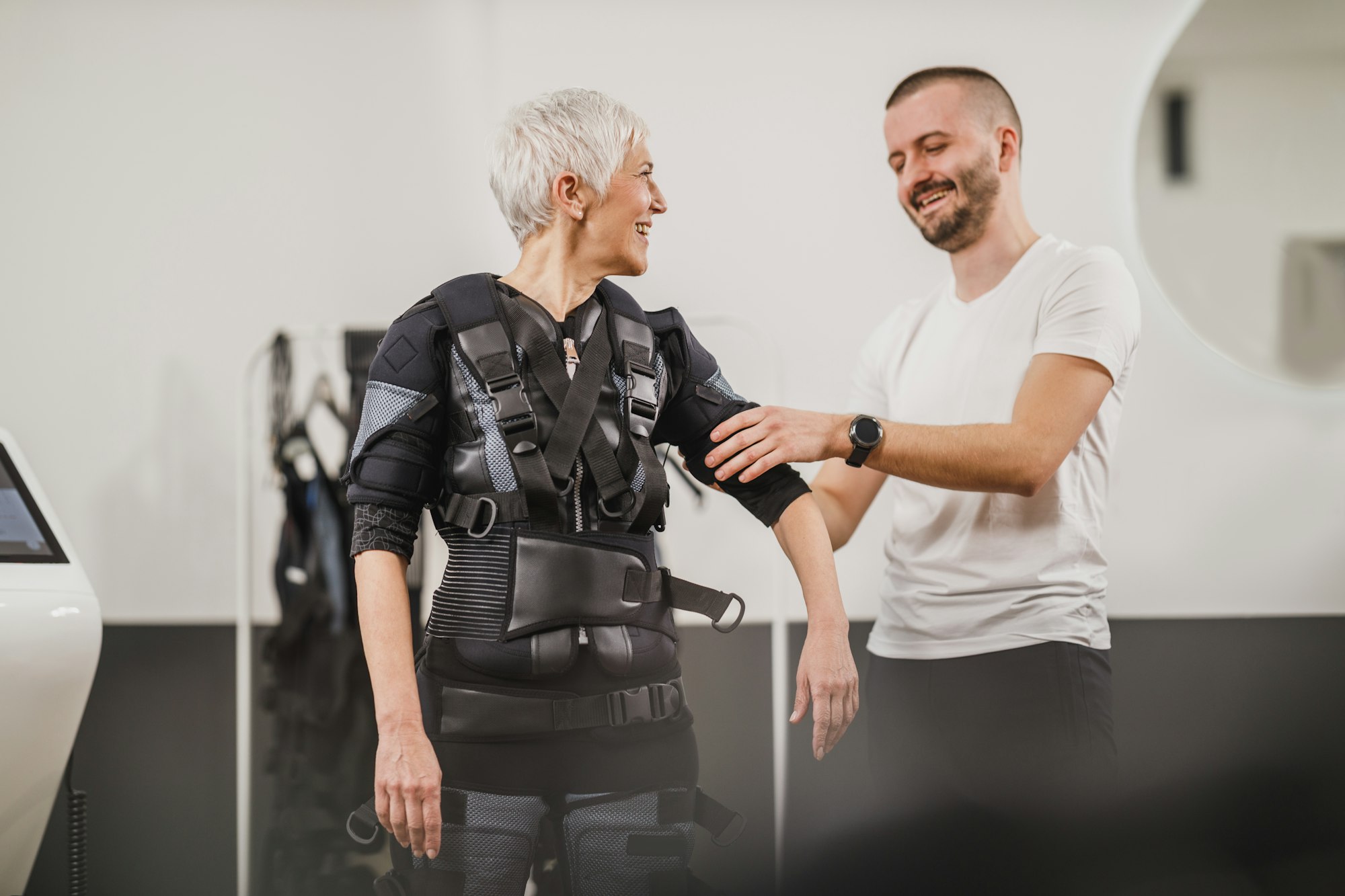 Fitness Instructor Putting An Ems Suit To A Woman