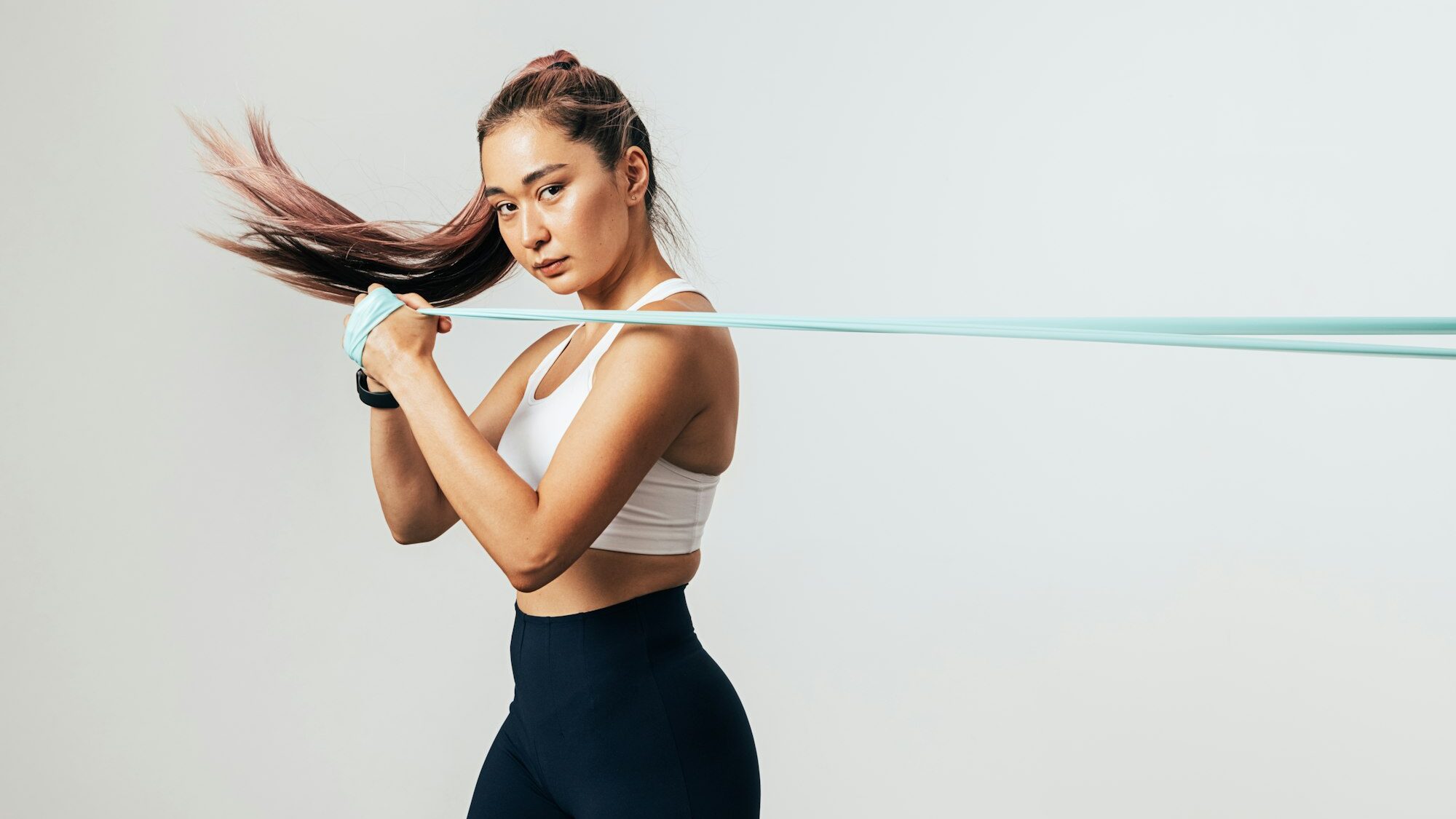 Fitness woman exercising with resistance band looking at camera