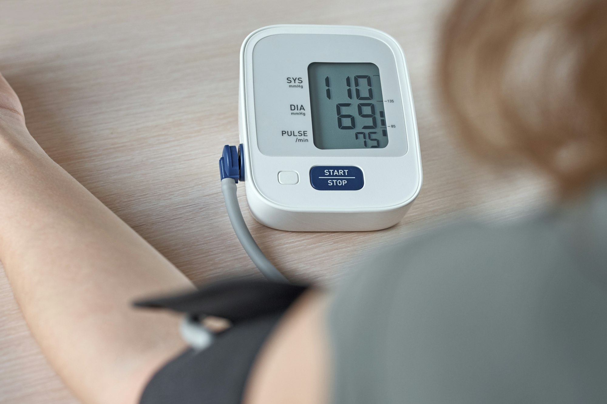 Woman measuring blood pressure with an electric digital monitor. Healthcare and medicine concept