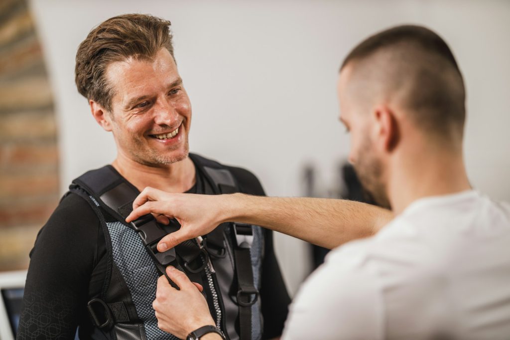 Fitness Instructor Putting An Ems Suit To A Man