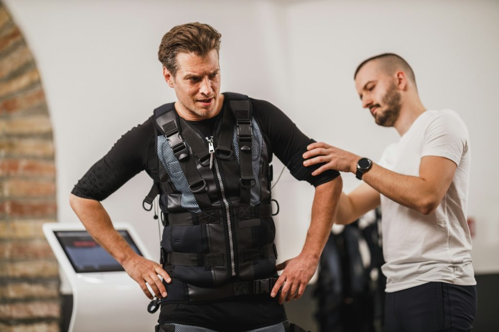 Fitness Instructor Putting An Ems Suit To A Man