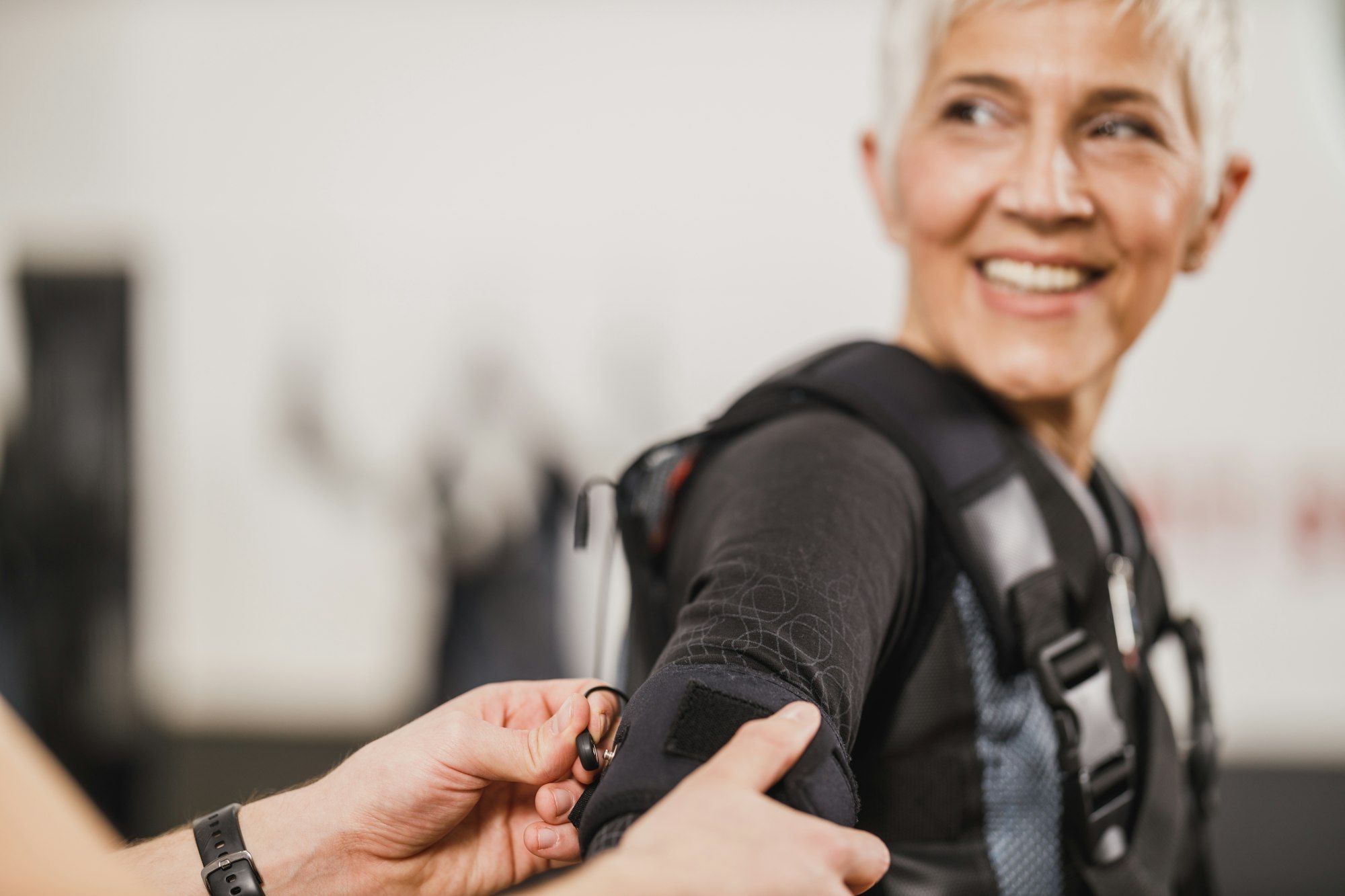 Fitness Instructor Putting An Ems Suit To A Woman