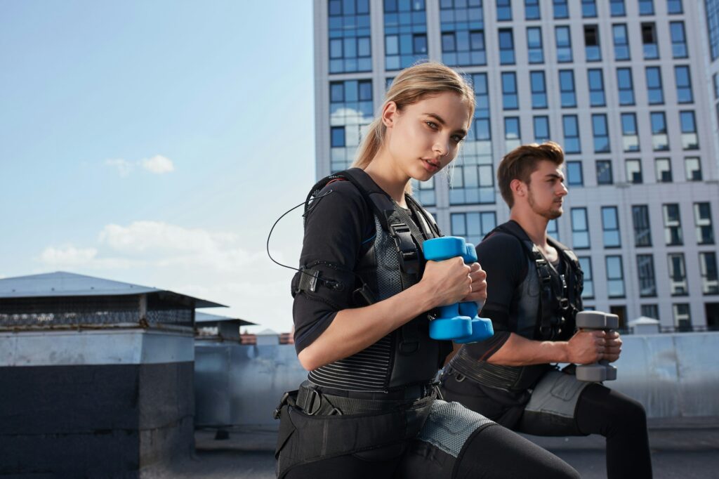 two awesome young people are doing exercises with ems suits